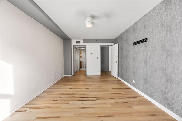 hallway with light wood-type flooring and a paneled ceiling