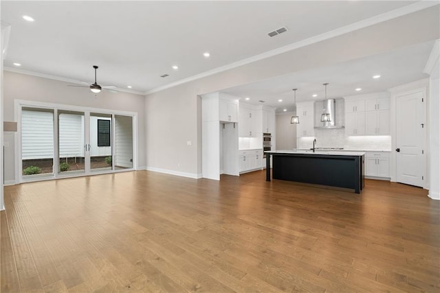 unfurnished living room with light wood-type flooring, ceiling fan, crown molding, and sink