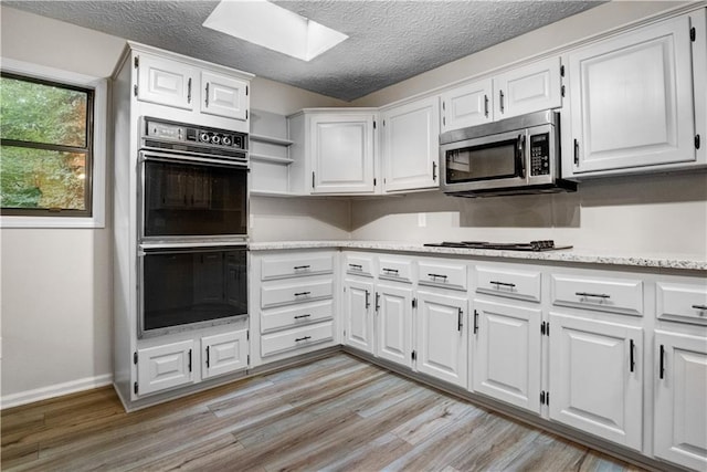 kitchen featuring white cabinets, a skylight, and black appliances