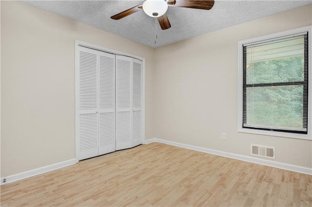 unfurnished bedroom with ceiling fan, a textured ceiling, light hardwood / wood-style flooring, and a closet