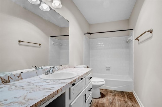 full bathroom with hardwood / wood-style floors, tiled shower / bath combo, vanity, and toilet