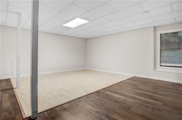 basement with a drop ceiling and dark hardwood / wood-style floors