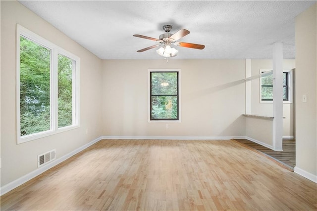 spare room featuring light wood-type flooring, ceiling fan, and a textured ceiling