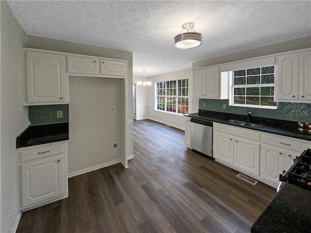 kitchen with dark countertops, dark wood-type flooring, stainless steel dishwasher, white cabinetry, and a sink