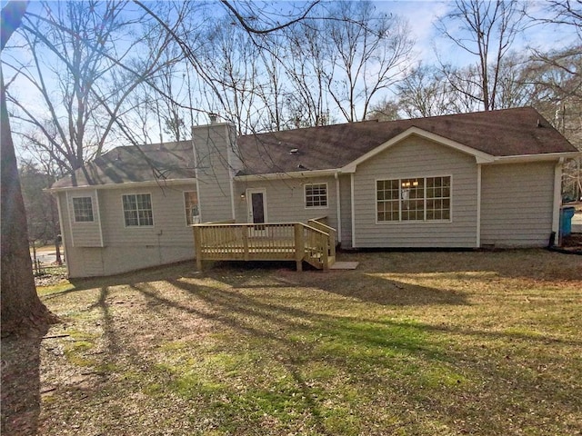 rear view of property featuring a chimney, a lawn, and a wooden deck