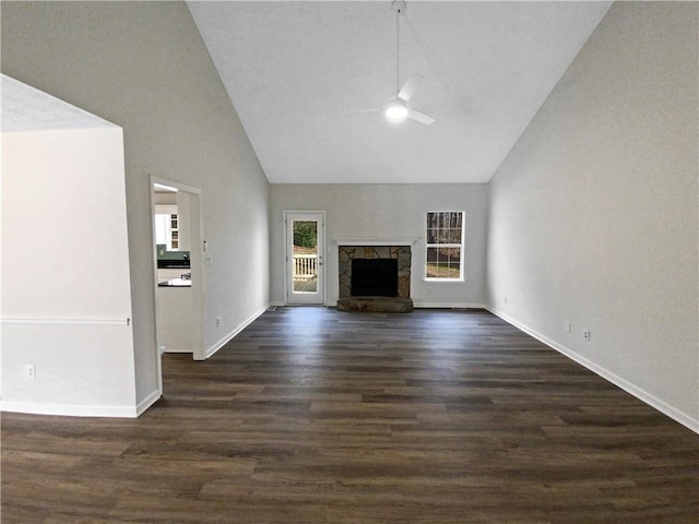 unfurnished living room featuring dark wood-style floors, baseboards, a stone fireplace, and ceiling fan