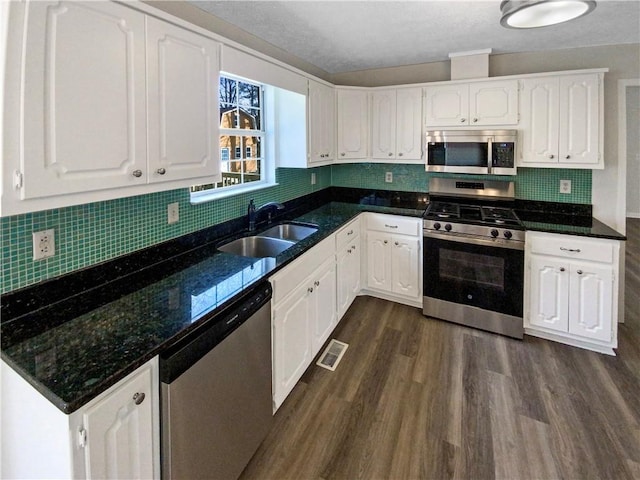 kitchen with a sink, appliances with stainless steel finishes, white cabinets, and dark wood finished floors