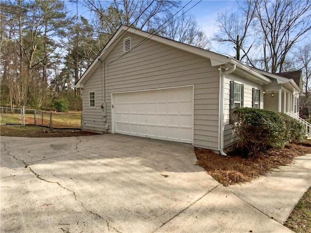 garage with concrete driveway and fence