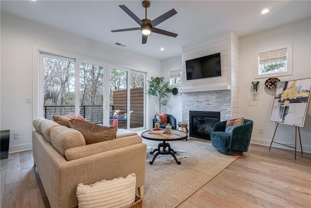 living room featuring a fireplace, light hardwood / wood-style floors, and ceiling fan