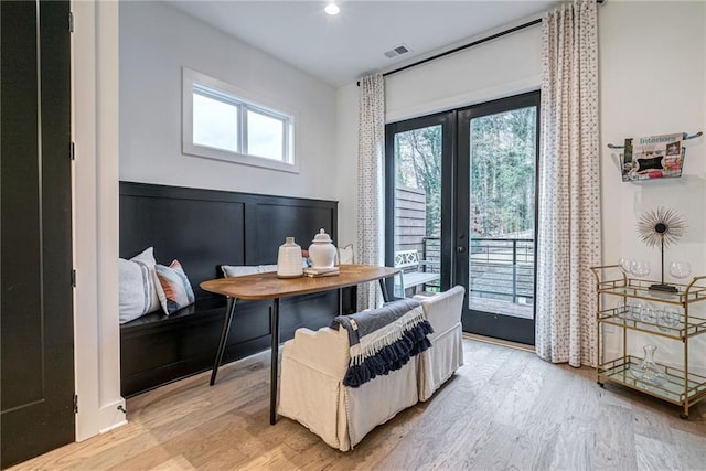 living area featuring a wealth of natural light, light wood-type flooring, and french doors