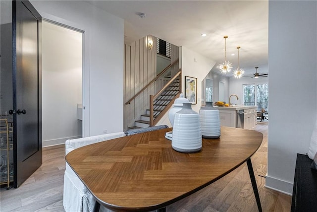 dining area featuring sink, ceiling fan with notable chandelier, and light hardwood / wood-style flooring