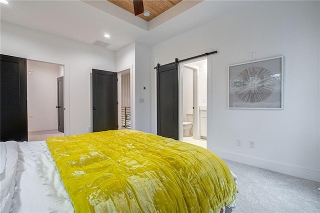 unfurnished bedroom featuring connected bathroom, light colored carpet, a raised ceiling, a barn door, and wooden ceiling