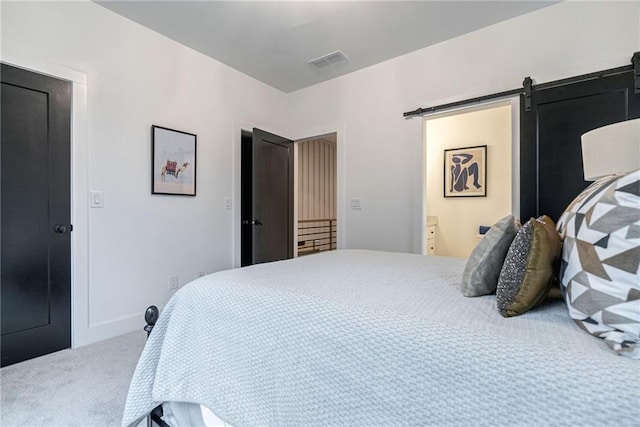 bedroom featuring ensuite bathroom, a barn door, and carpet