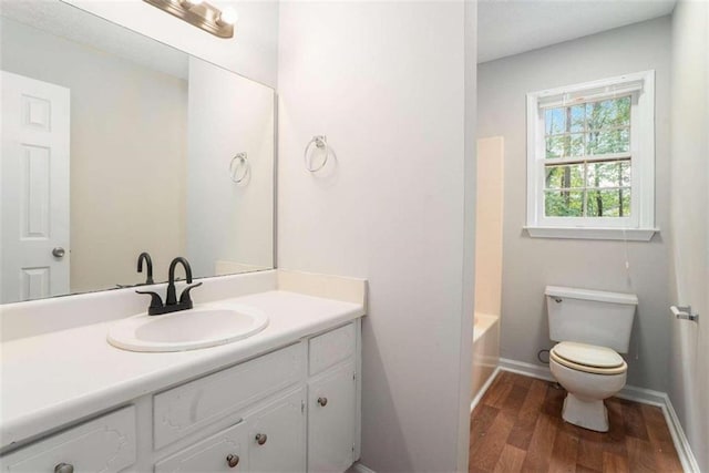 bathroom featuring vanity, wood finished floors, toilet, and baseboards