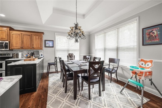 dining room featuring dark hardwood / wood-style flooring, a notable chandelier, a raised ceiling, and a healthy amount of sunlight