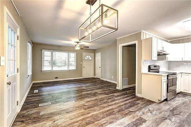 kitchen featuring dark wood finished floors, under cabinet range hood, light countertops, stainless steel range with electric stovetop, and backsplash