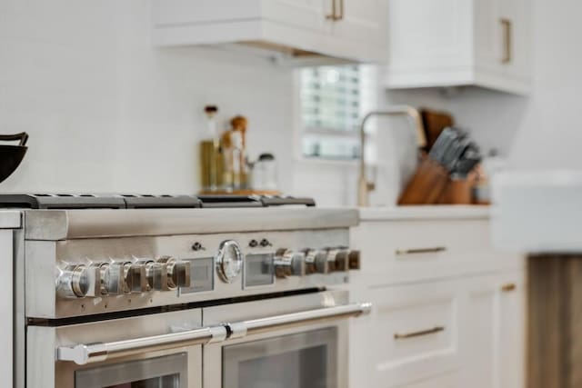 room details featuring white cabinetry and high end stainless steel range oven