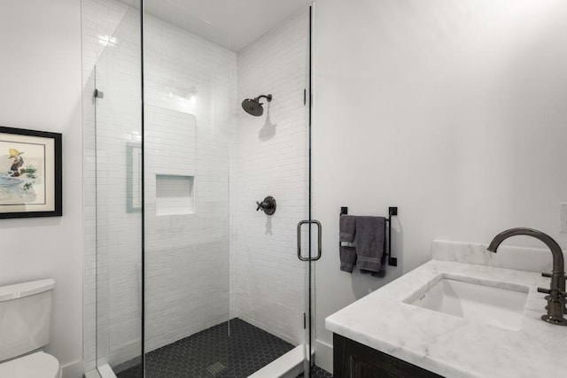 bathroom featuring vanity, toilet, and a shower with door