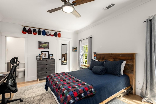 bedroom featuring hardwood / wood-style floors, ensuite bath, ceiling fan, and ornamental molding