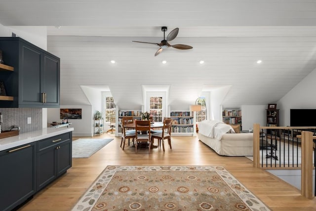 living room with light wood-type flooring, vaulted ceiling, and ceiling fan