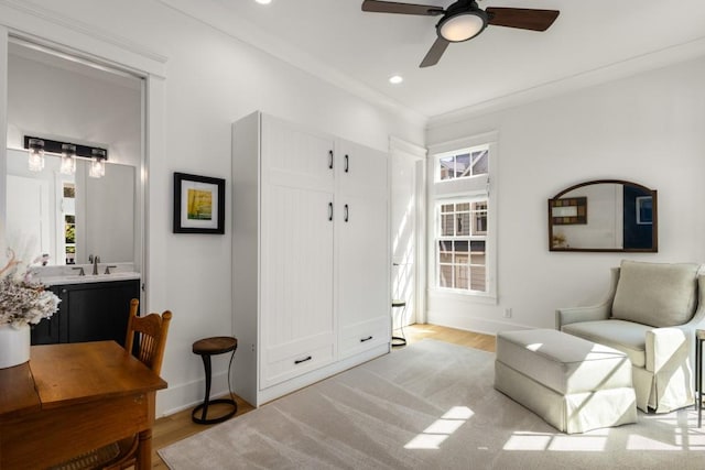 sitting room featuring ceiling fan, ornamental molding, sink, and light hardwood / wood-style flooring