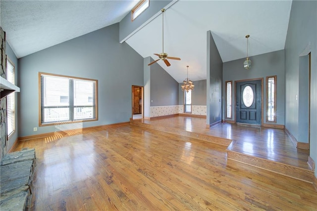 entrance foyer featuring plenty of natural light, ceiling fan with notable chandelier, and hardwood / wood-style flooring