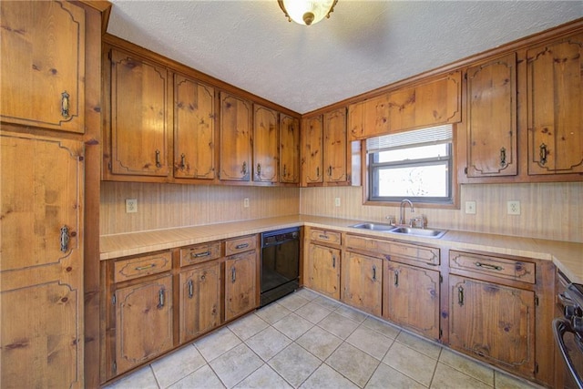 kitchen featuring light countertops, light tile patterned floors, brown cabinetry, black appliances, and a sink