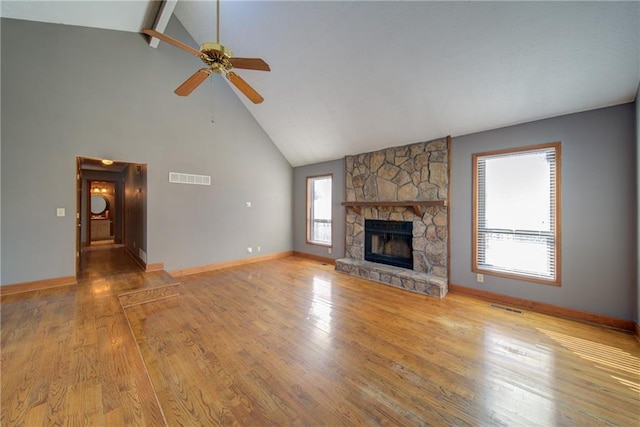 unfurnished living room featuring ceiling fan, visible vents, a stone fireplace, and wood finished floors