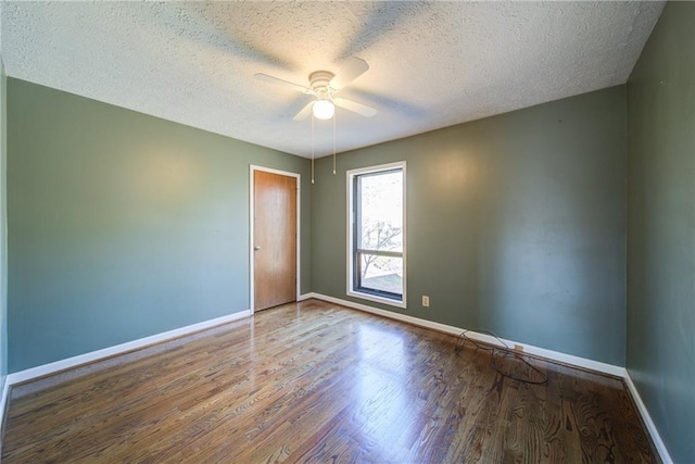 spare room with a ceiling fan, wood finished floors, baseboards, and a textured ceiling