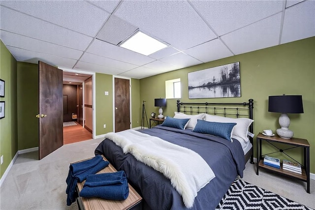 bedroom featuring a drop ceiling, baseboards, and carpet floors