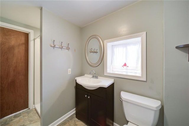 full bathroom with baseboards, toilet, walk in shower, and vanity