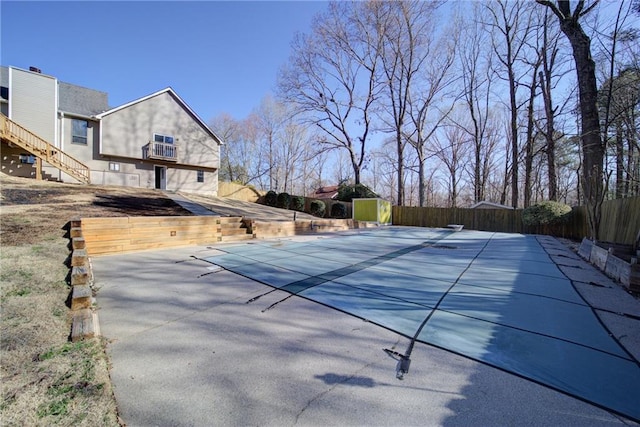 view of swimming pool with fence, an outdoor structure, a diving board, a fenced in pool, and a patio area