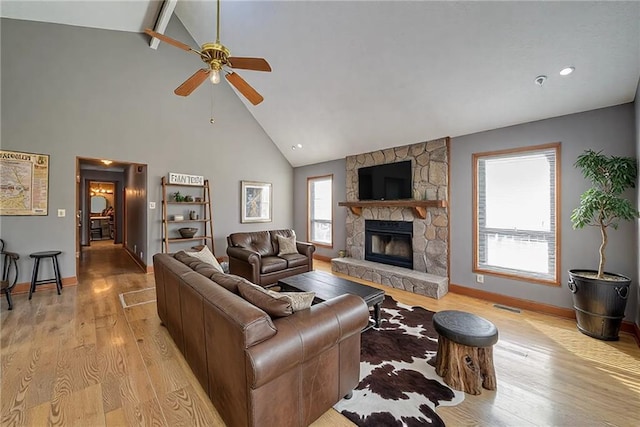 living room with light wood finished floors, visible vents, baseboards, a fireplace, and a ceiling fan