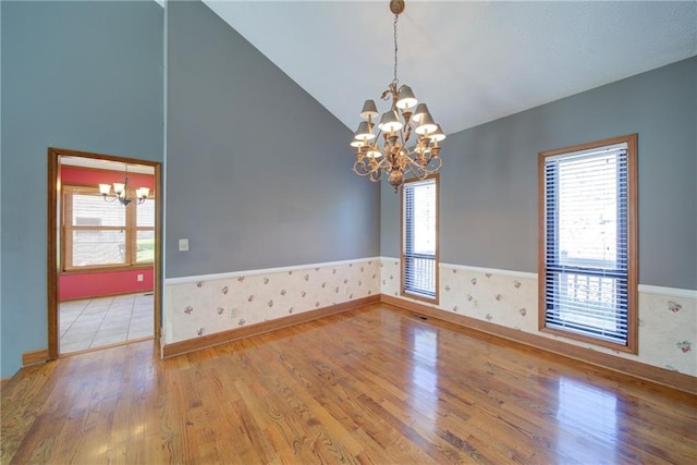 unfurnished room with a notable chandelier, a healthy amount of sunlight, and wainscoting