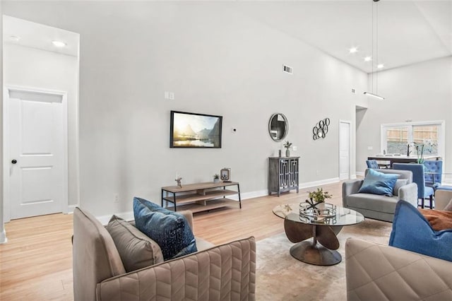 living room featuring a towering ceiling and light wood-type flooring