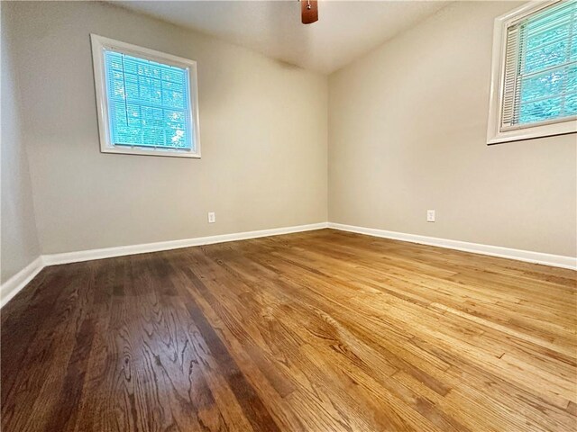 spare room featuring ceiling fan, a healthy amount of sunlight, and hardwood / wood-style floors