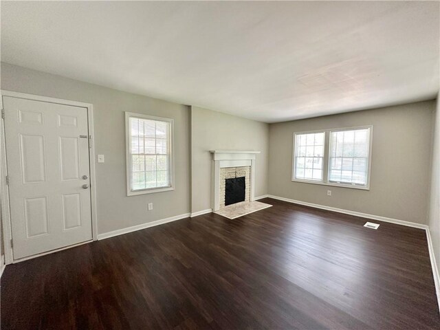 unfurnished living room with dark wood-type flooring and a fireplace