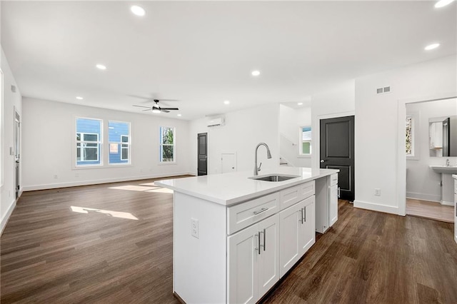 kitchen with white cabinetry, sink, ceiling fan, dark wood-type flooring, and a center island with sink