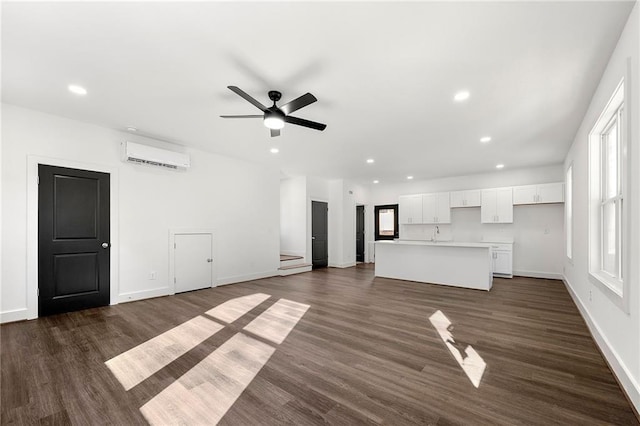 unfurnished living room with ceiling fan, dark hardwood / wood-style flooring, and a wall mounted AC