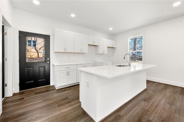 kitchen featuring white cabinetry, sink, an island with sink, and dark wood-type flooring