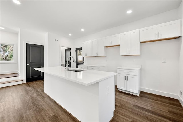 kitchen featuring white cabinets, dark hardwood / wood-style flooring, sink, and an island with sink