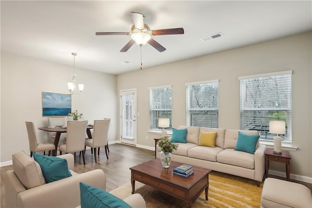 living room with ceiling fan with notable chandelier and light hardwood / wood-style flooring