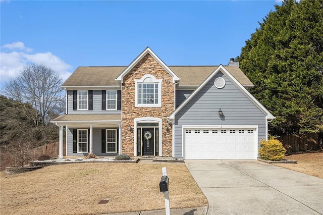 traditional home featuring an attached garage, fence, stone siding, concrete driveway, and a chimney