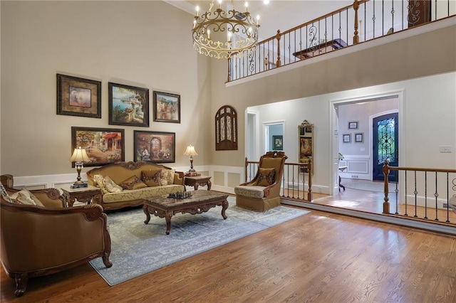 living room featuring a notable chandelier, wood-type flooring, and a towering ceiling