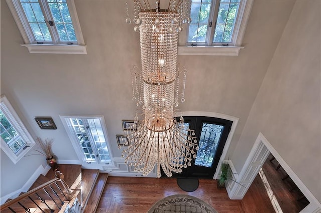 entrance foyer with french doors, dark hardwood / wood-style floors, a chandelier, and a towering ceiling