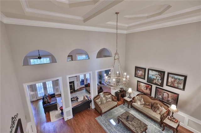 living room featuring a notable chandelier, a tray ceiling, dark wood-type flooring, and crown molding