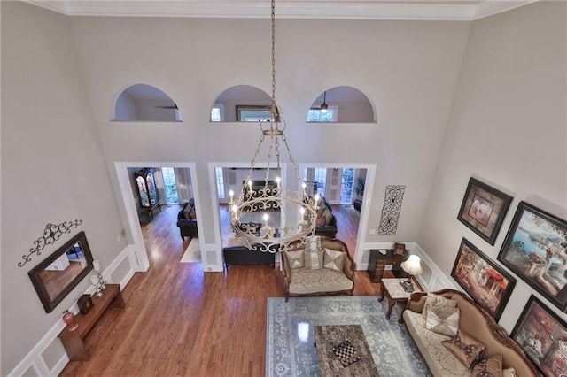 living room with a towering ceiling, crown molding, a chandelier, and dark hardwood / wood-style flooring