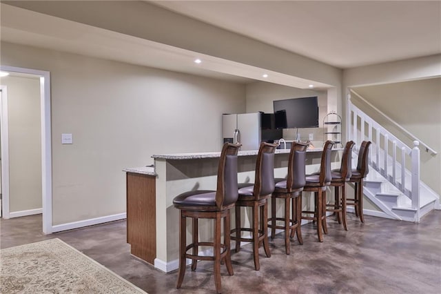 bar with light stone counters and stainless steel fridge