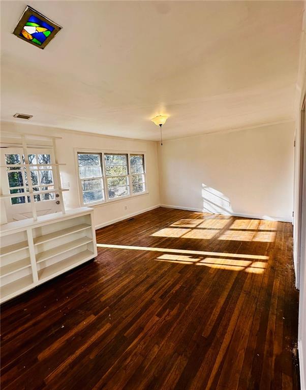 empty room with visible vents, baseboards, and hardwood / wood-style flooring