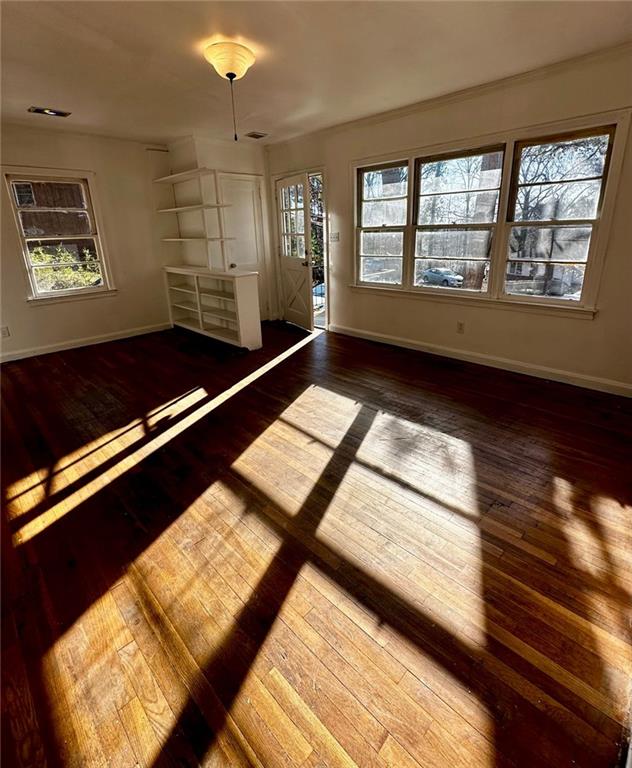 empty room with baseboards, wood-type flooring, and visible vents